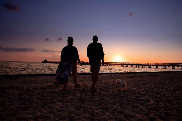 Par går tur med hunden med solnedgangen i baggrunden