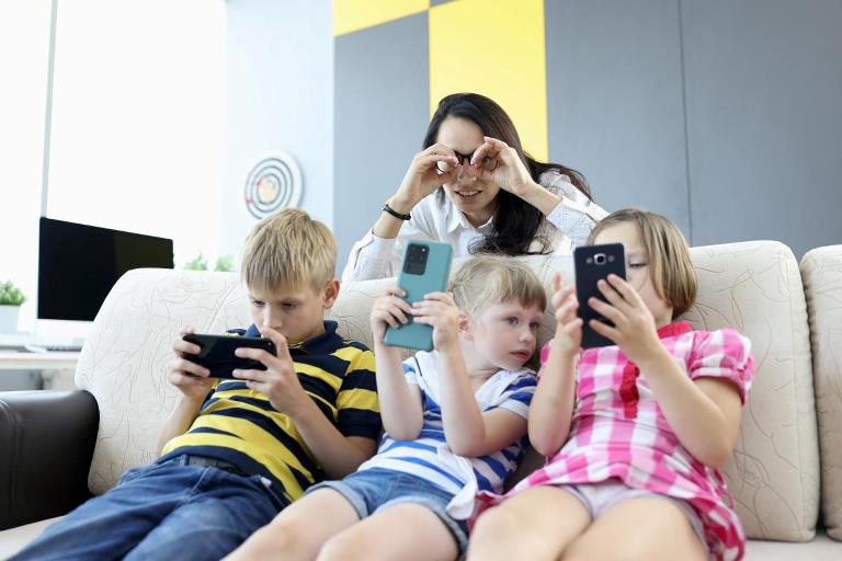 Børn der sidder i sofa og kigger på mobiler
