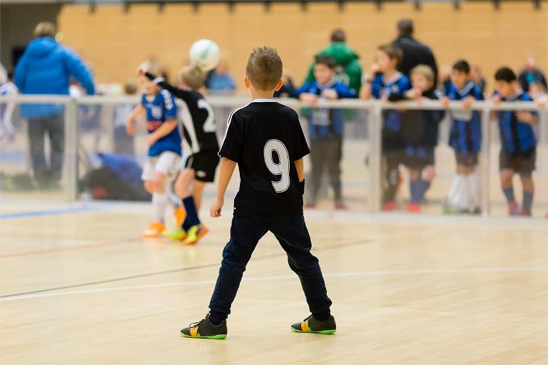 Børn spiller indendørsfodbold i idrætshal